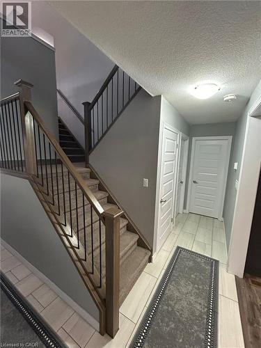 Staircase with wood newel posts, black metal balusters, and carpeted treads - 766 Freeport Street, London, ON 
