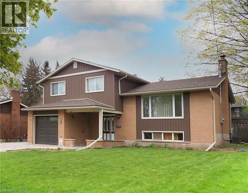 Two-story residence featuring a brick and vertical siding exterior, an attached garage, a covered front entry, multiple window styles, and a gabled roofline - 76 Cloverdale Crescent, Kitchener, ON 