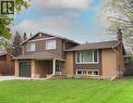 Two-story residence featuring a brick and vertical siding exterior, an attached garage, a covered front entry, multiple window styles, and a gabled roofline - 76 Cloverdale Crescent, Kitchener, ON 