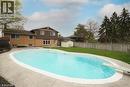 Fenced backyard featuring an in-ground swimming pool with a diving board, surrounding concrete patio, and a manicured lawn - 76 Cloverdale Crescent, Kitchener, ON 