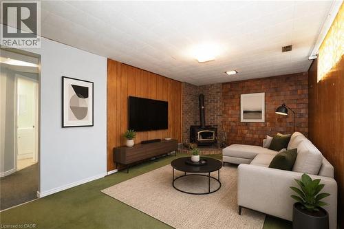 Living area featuring wood paneling, a shingle-textured accent wall, and wood-burning stove - 76 Cloverdale Crescent, Kitchener, ON 