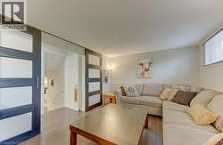 Spacious living area featuring wood-finish flooring, sliding panel doors, and a window with blinds - 