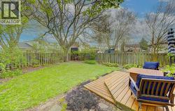 Expansive backyard featuring a large lawn area, mature trees, and a wooden deck with a small set of steps - 