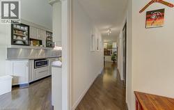 Hardwood flooring extends through the hallway, featuring recessed lighting and white walls - 