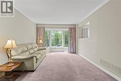 Living area featuring a bay window with natural light, crown molding, a neutral color palette, and wall-to-wall carpeting - 