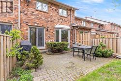 Brick exterior featuring a paver patio, sliding glass door, bay window, and wooden privacy fencing - 