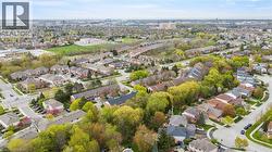 Expansive aerial perspective showcasing a residential area with varied housing styles, mature trees, and a clear sky backdrop - 