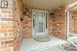 Brick facade entry with a light gray storm door and sidelights - 