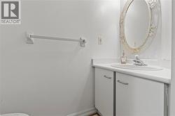 White vanity with an integrated sink, polished chrome faucet, and decorative oval mirror - 