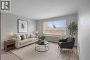 Virtually staged Living room featuring and laminate flooring and large window - 57 Mericourt Road Unit# 310, Hamilton, ON 
