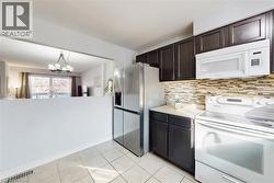 Kitchen featuring dark wood cabinetry, a mosaic tile backsplash, and a stainless steel refrigerator - 
