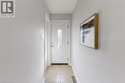 Entryway featuring a white door with decorative glass inserts, light tile flooring, and light gray wall paint - 