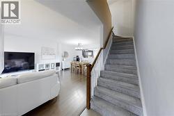 Staircase with light gray carpeting and a wood handrail - 