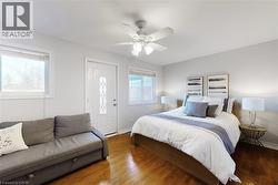 Bright room featuring wood-finish flooring, a ceiling fan with integrated lighting, and white walls - 