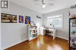 Room featuring wood-finish flooring, a ceiling fan with integrated lighting, and a single window with blinds - 
