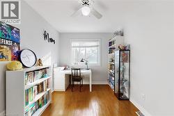 Bright room featuring wood-finish flooring, a ceiling fan with integrated lighting, and a white-framed window with blinds - 
