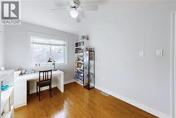 Spacious room featuring wood-finish flooring, light grey walls, and a large window with white blinds - 