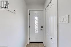 Entryway featuring a white door with decorative glass inserts, a built-in closet with bifold doors, tile flooring, and a wall-mounted coat rack - 