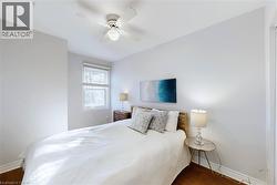 Bedroom featuring wood-finish flooring, a ceiling fan with integrated lighting, a window with horizontal blinds, and a built-in closet visible on the right - 