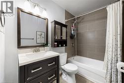 Bathroom featuring a dark wood-finish vanity with a white countertop and integrated sink, chrome faucet, and a large framed mirror - 