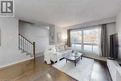 Bright living area featuring wood-finish flooring, a large picture window, and light-toned wall finishes - 
