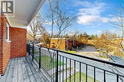 Outdoor balcony featuring wood decking, a black metal railing, and a brick exterior wall - 