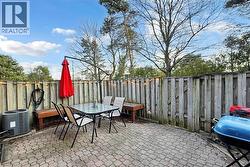Paver patio area featuring a privacy fence, integrated wooden benches, and overhead string lighting - 