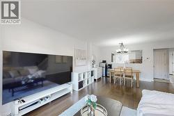 Open-concept living area featuring wood-finish flooring, white walls, and a recessed pass-through to a kitchen area - 