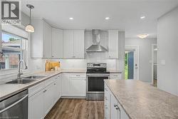 Modern kitchen featuring white shaker cabinetry, stainless steel appliances, vinyl flooring, recessed lighting, and a kitchen island with countertop space - 