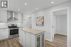 Modern kitchen featuring white shaker cabinetry, stainless steel appliances, a white subway tile backsplash, and wood-finish flooring - 