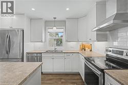 Updated kitchen featuring white shaker cabinetry, stainless steel appliances, a subway tile backsplash, light-toned countertops, and vinyl flooring - 