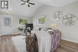 Living area with cathedral ceiling, vinyl flooring, and multiple windows - 