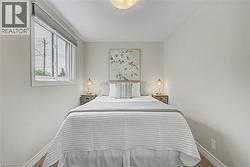 Bedroom featuring a window with energy efficient window shades, ceiling-mounted light fixture, and light-toned walls - 
