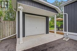 Detached garage with a white panel door, concrete drive, and dark vertical siding - 