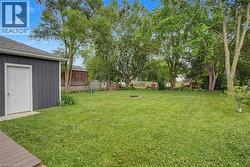 Expansive backyard featuring a lush lawn and mature trees - 