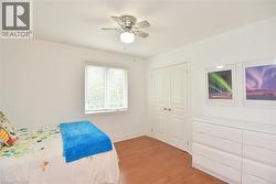 Bedroom featuring wood-finish flooring, white walls, and a window with blinds - 