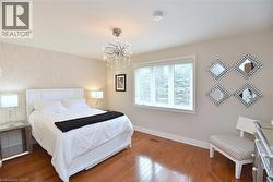 Bright room featuring rich wood-finish flooring and a decorative chandelier - 