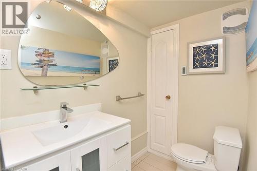 Bathroom featuring a white vanity with integrated sink, chrome faucet, and an organically shaped wall mirror with a glass shelf - 4299 Lakeshore Road, Burlington, ON - Indoor Photo Showing Bathroom