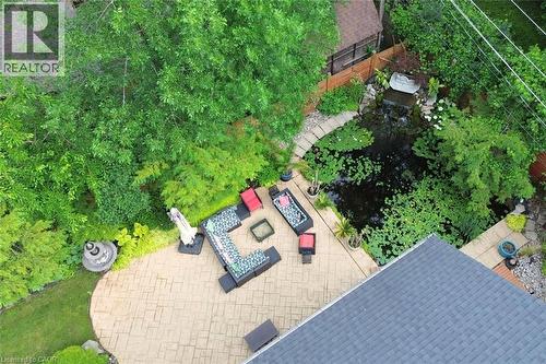 Stamped concrete patio with a tiered fountain, surrounded by mature trees and lush landscaping - 4299 Lakeshore Road, Burlington, ON - Outdoor