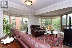 Expansive living area featuring wood-finish flooring, crown molding, and large bay windows - 
