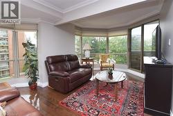 Living area featuring expansive windows, wood-finish flooring, and crown molding - 