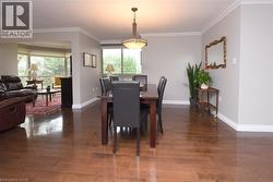 Dining area featuring wood-finish flooring, a contemporary ceiling fixture, and crown molding - 