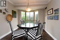 Bay window with multiple glass panes, crown molding, a central hanging light fixture, neutral wall paint, and dark tile flooring - 