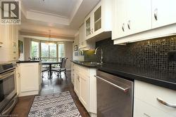 Gourmet kitchen featuring white cabinetry, stainless steel appliances, dark countertops, and a black mosaic tile backsplash - 