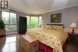Room featuring a bay window, wood-finish flooring, light grey walls, and crown molding - 