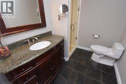 Bathroom featuring a dark wood-finish vanity with a granite countertop, undermount sink, and brushed nickel faucet - 