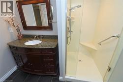 Bathroom featuring a dark wood vanity with a stone countertop and an oval undermount sink - 