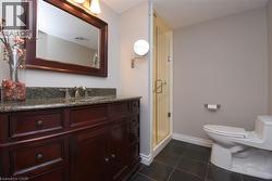 Bathroom featuring a dark wood vanity with a granite countertop and integrated sink - 
