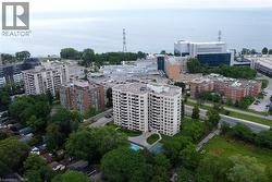 Aerial perspective showcasing a high-rise condominium building with multiple balconies, a ground-level swimming pool, and a tennis court - 