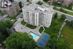 High-rise residential building featuring multiple balconies, a ground-level swimming pool, and an outdoor tennis court - 